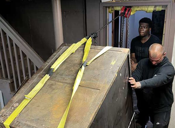 2 men lifting a heavy safe